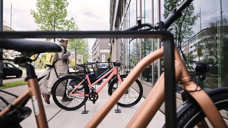 Eine Frau kommt mit ihrem Fahrrad am Büro an